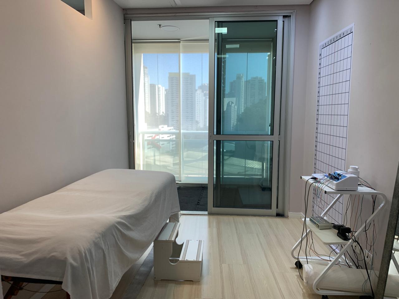 Sala de atendimento com vista para a cidade e equipamentos de eletroterapia
