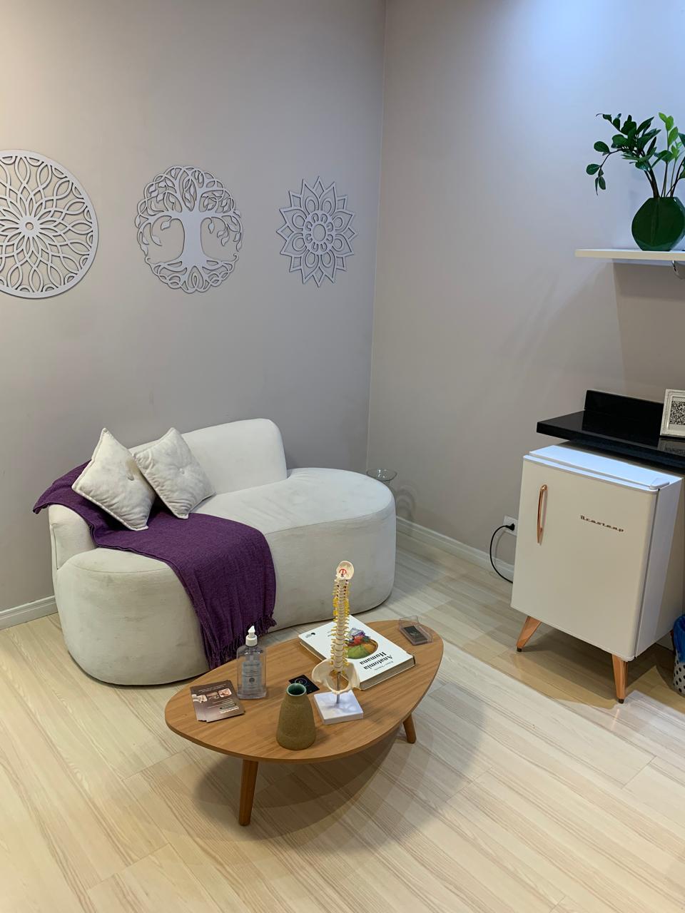 Sala de espera da clínica, com poltrona branca e decoração acolhedora
