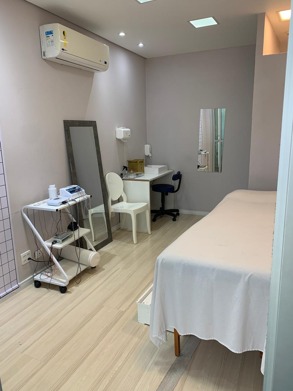 Sala de fisioterapia climatizada com maca, espelho e aparelhos
